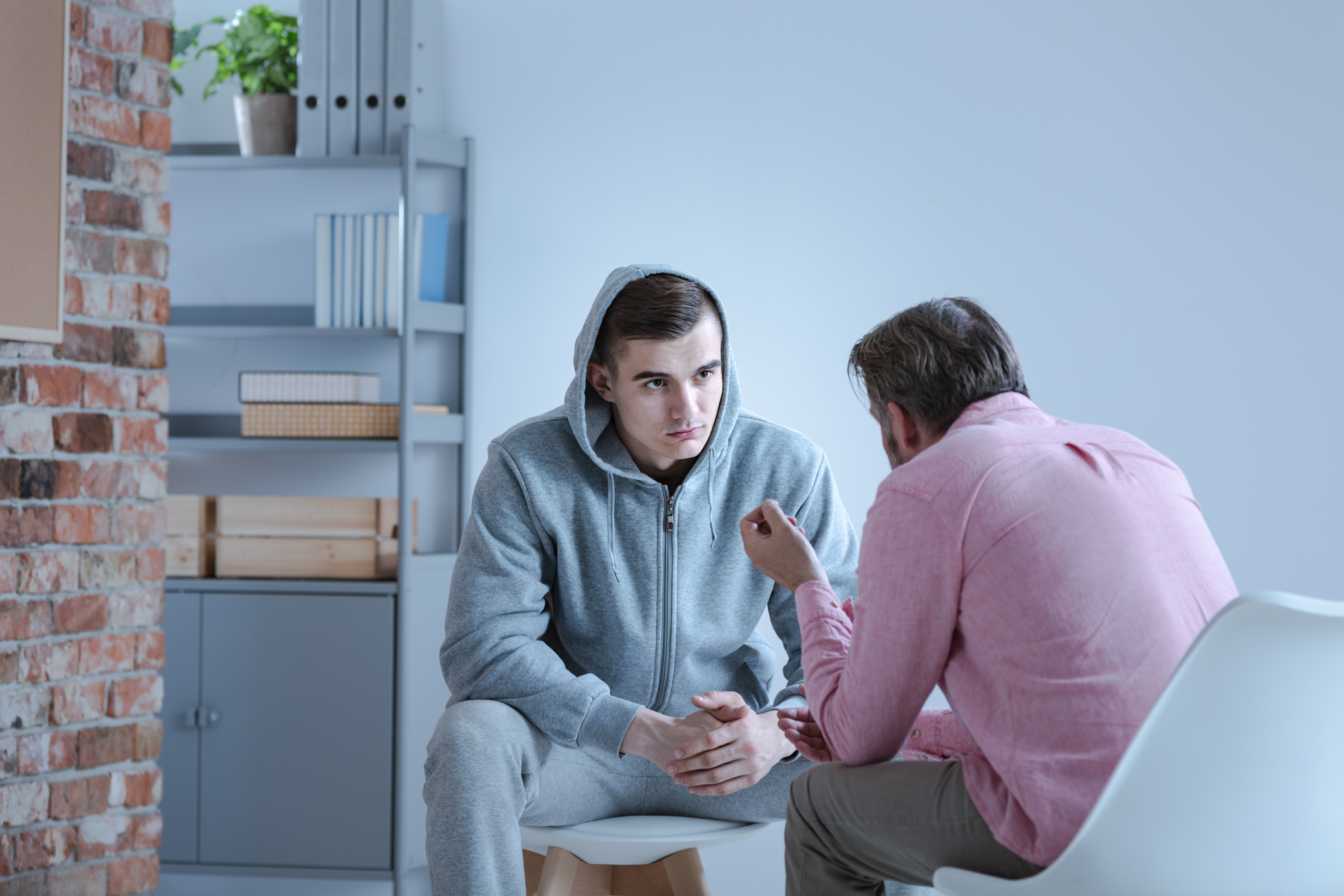 A psychology specialist explaining an action plan for recovery to a troubled teenage boy during outpatient rehab.